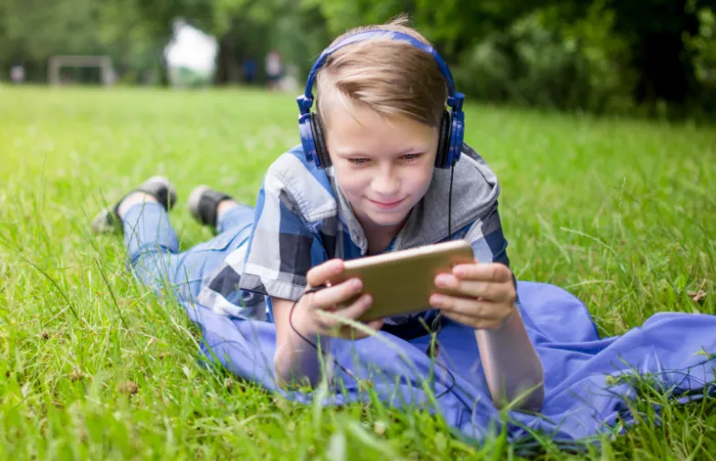 kind in gras met mobiele telefoon
